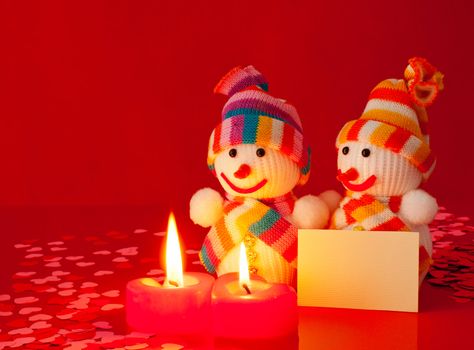 Two snowmen with two burning heart shaped candles