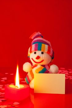 Snowman with burning heart shaped candle and blank card