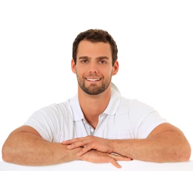 Attractive young guy standing behind white wall. All on white background.