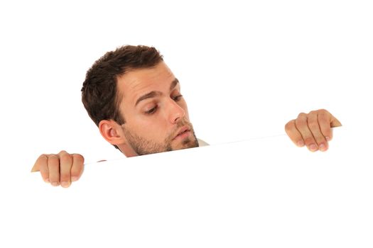 Curious young guy behind white wall. All on white background.