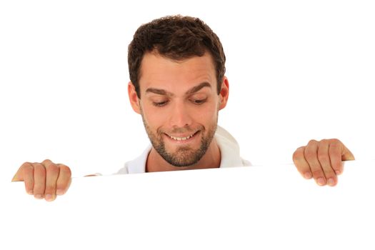 Curious young guy behind white wall. All on white background.