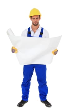 Full length shot of a construction worker studying a construction plan. All on white background.