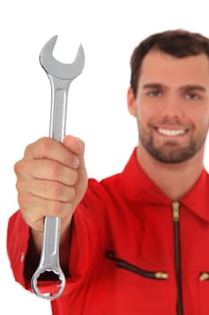 Smiling mechanic holding wrench. Selective focus on hand in foreground. All on white background.