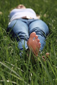 Attractive young woman resting outside on green meadow.