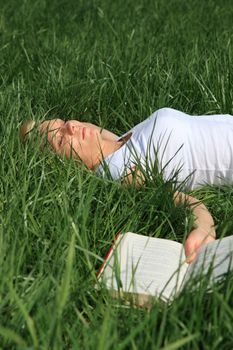 Attractive young woman resting outside on green meadow.