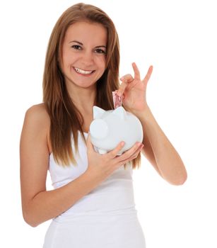 Attractive brunette girl puts money in her piggy bank. All on white background.