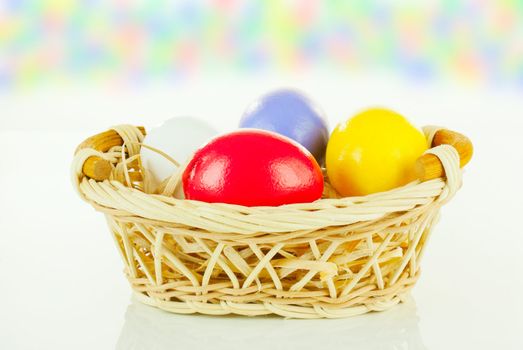 Colorful Easter eggs in a basket against colorful background