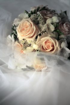 Wedding bouquet from beige roses on a background of a wedding dress