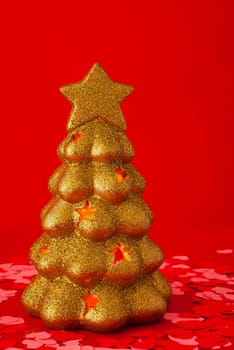 Shiny golden evergreen tree against red background