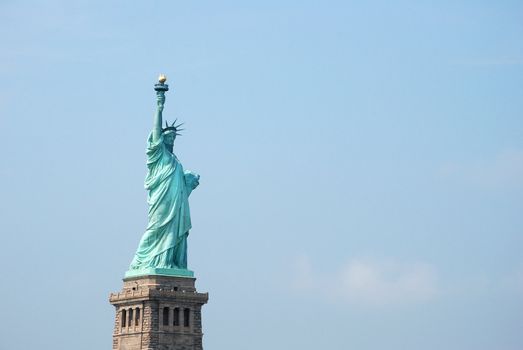 The Statue of Liberty stands proudly against a powder blue sky