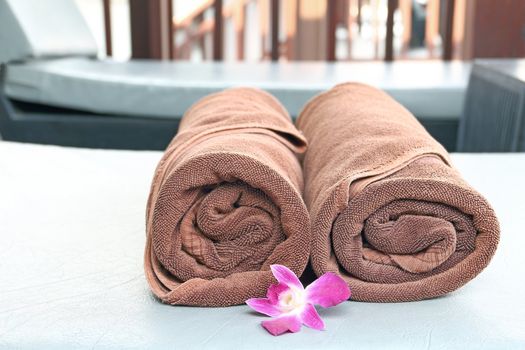 Rolled up of two brown towels on sun lounger chair