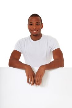 Attractive black man standing behind white wall. All on white background.