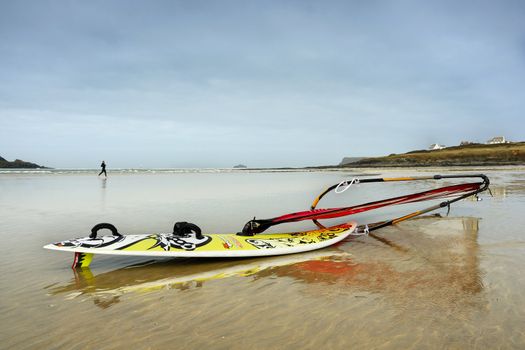 Woman running on the beach. Wind surfer in foreground.