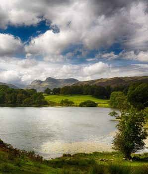 Sun illuminating Langdale Pikes with Loughrigg Tarn in foreground