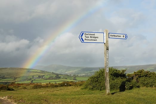 Rainbow over a signpost on dartmoor, Devon, UK.
