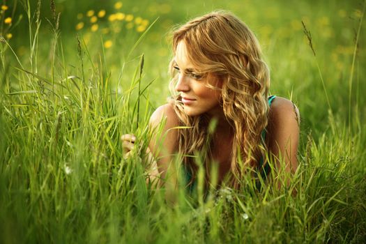 blonde lays on green grass