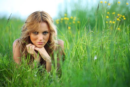 blonde lays on green grass