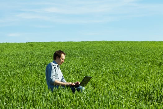 young man using laptop in the field