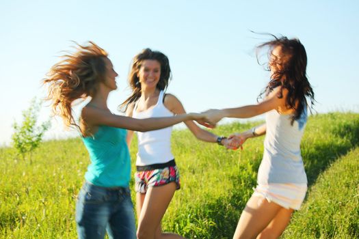 girlfriends round dance on a green grassy field