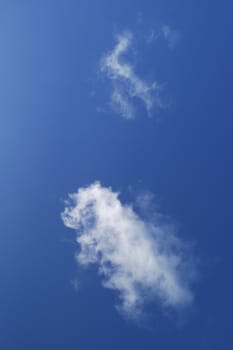 Simple composition of a blue sky and two white wispy clouds.