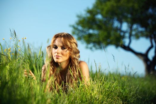 blonde lays under the tree 