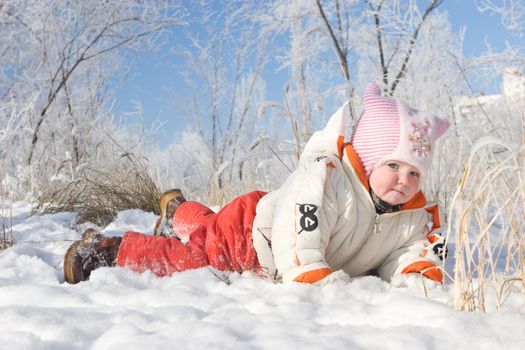 happy child lays on white snow