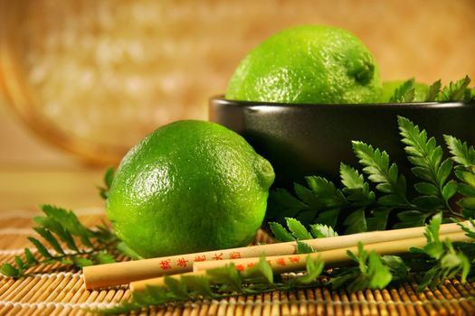 Limes with chopsticks with bamboo mat/ Asian culinary influence 