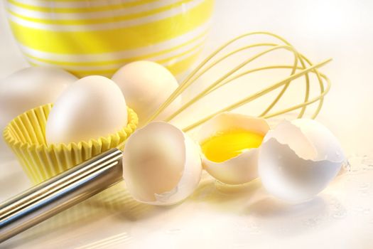 Yellow egg yolk with eggs and whisk for baking