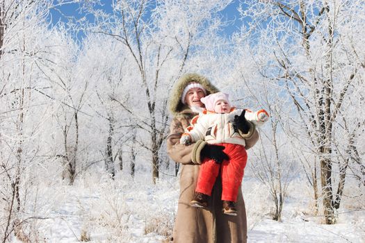 a mother and a child in a snow-covered winter forest looking up