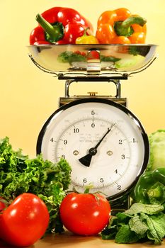 Fresh veggies on kitchen scale with yellow background