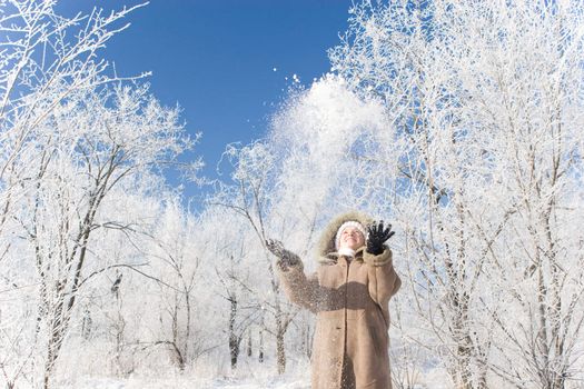 a girl throwing up snow in the winter forest