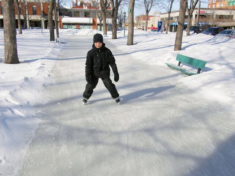 picture of a young boy ice skating in a city park in winter