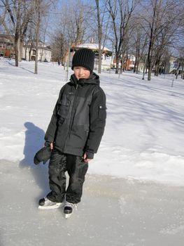 picture of a young boy ice skating in a city park in winter