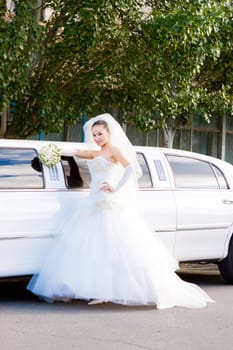 a beautiful bride near the long white wedding car
