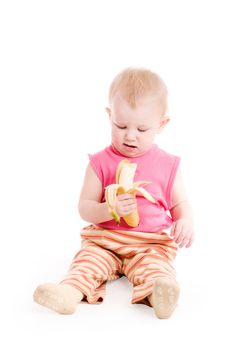 a small girl sitting on the floor and eating a banana