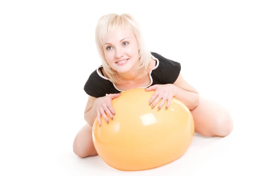 a beautiful smiling blond girl with a big fitness ball on the floor
