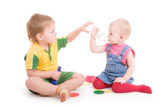 a small boy gives water in a bottle to the small girl