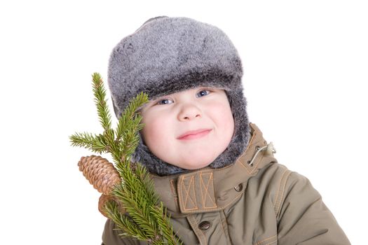 a smiling boy dressed for winter with a branch of fur tree with cones