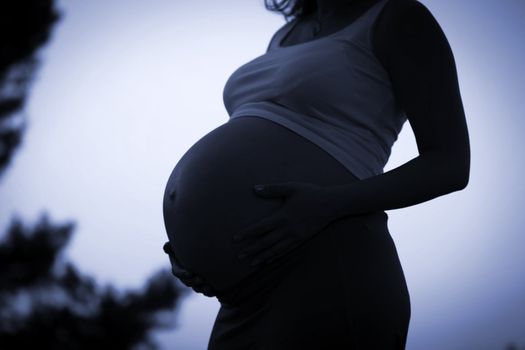 Pregnant woman holding belly with arms 9 month 