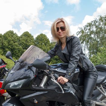 smiling biker girl dressed in leather clothes on a motorcycle