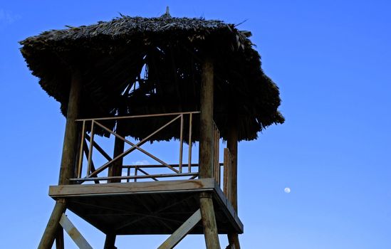 Tropical watchtower overlooking a beach silhouette at sunset