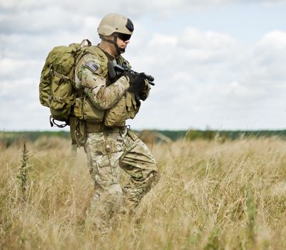 Soldiers  in full gear patrol the area in the desert