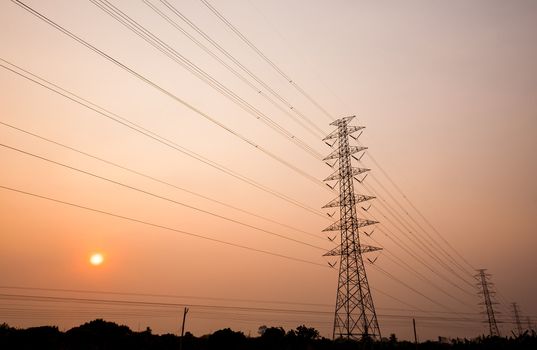 silhouette of power transmission towers with sunset in background