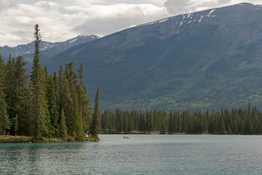 Peaceful and in total silence slowly floating over water in between forests and mountains.