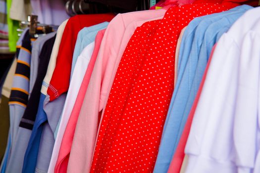 a lot of bright children's clothing on a hanger in the store