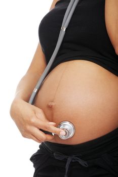 Belly closeup of a pregnant woman listening to her baby through the stethoscope, over a white background.