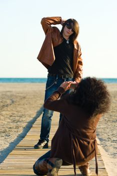 Woman taking photographs of a teenager on the beach