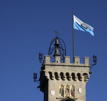 The flag of San Marino flying on top of a bell tower.