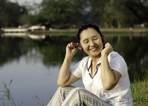 Outdoor portrait of beautiful asian woman listening music in headphones with closed eyes 
