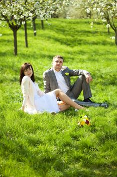  just married in a flowering garden sitting on the grass